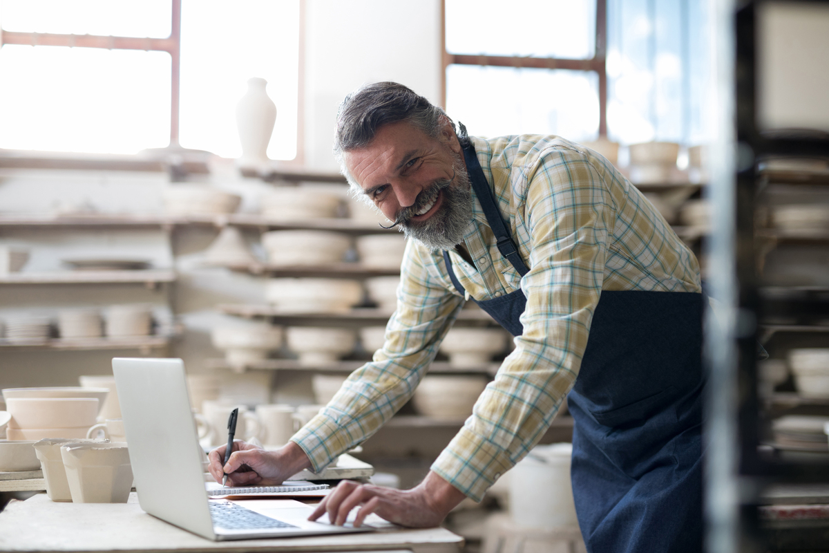 iFama features a happy potter who is working on his computer whilst standing in his factory